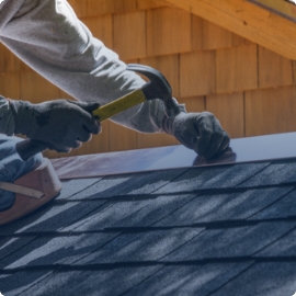Trabajador fijando tejas en techo de una casa